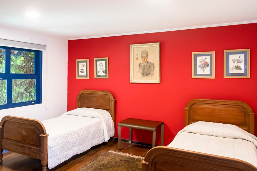 Quarto com parede vermelha e duas camas de madeira