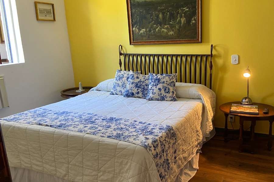 Quarto com parede amarela e cabeceira de ferro
