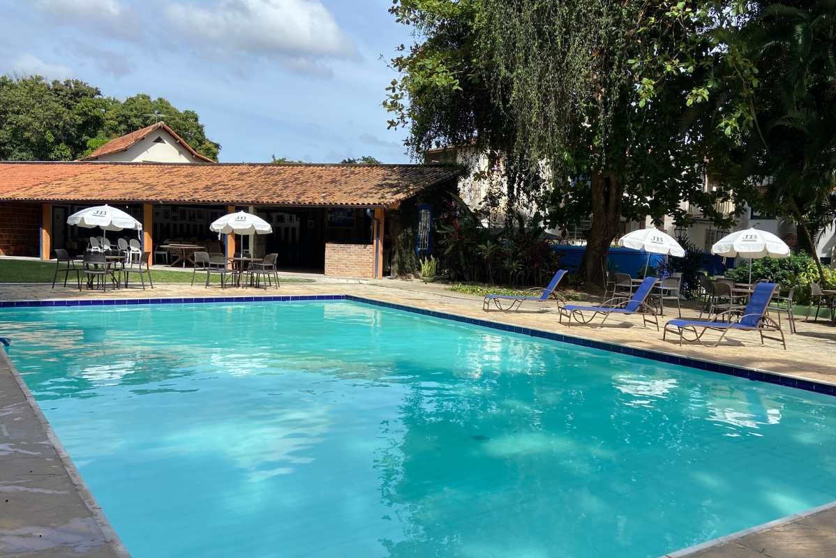 Piscina cercada por jardim e guarda-sóis